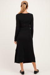 woman wearing a black long sleeve maternity dress with a side slit, viewed from the back