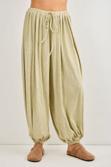 woman wearing light green high-waisted harem pants with a drawstring waist and gathered ankles