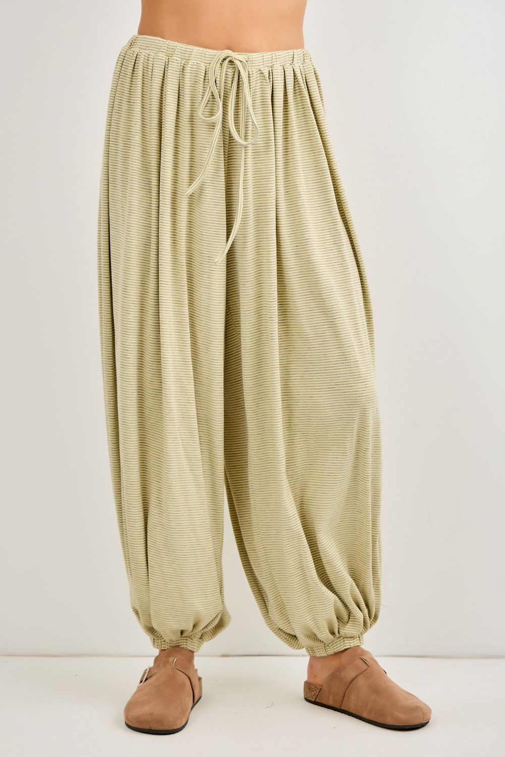 woman wearing light green high-waisted harem pants with a drawstring waist and gathered ankles