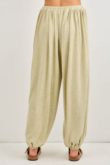 woman wearing light olive green relaxed fit harem pants with an elastic waistband and tapered cuffs