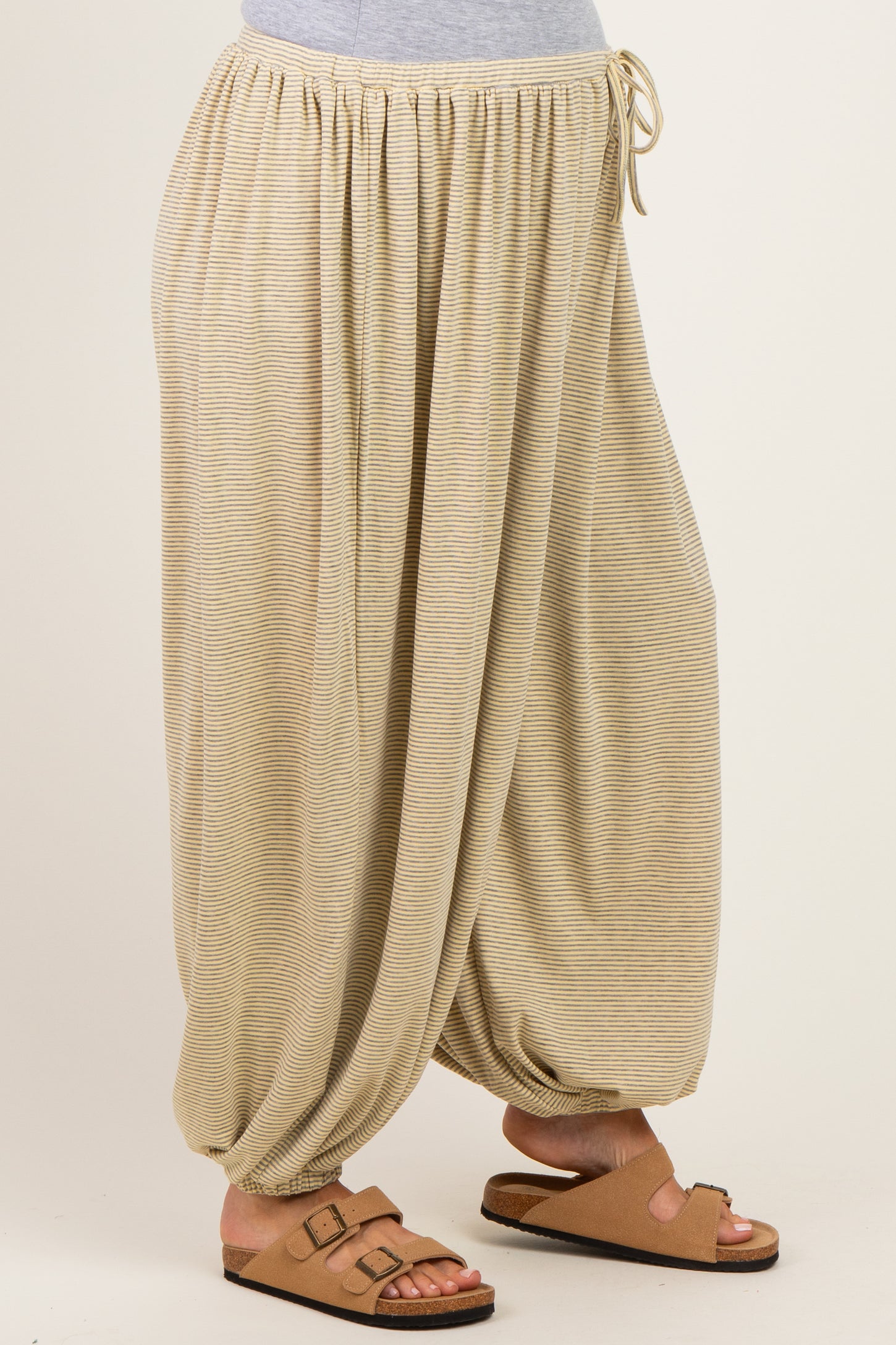 woman wearing beige striped maternity harem pants with an elastic waistband and gathered cuffs