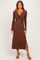 woman wearing a brown long sleeve maxi dress with a twist front and a side slit