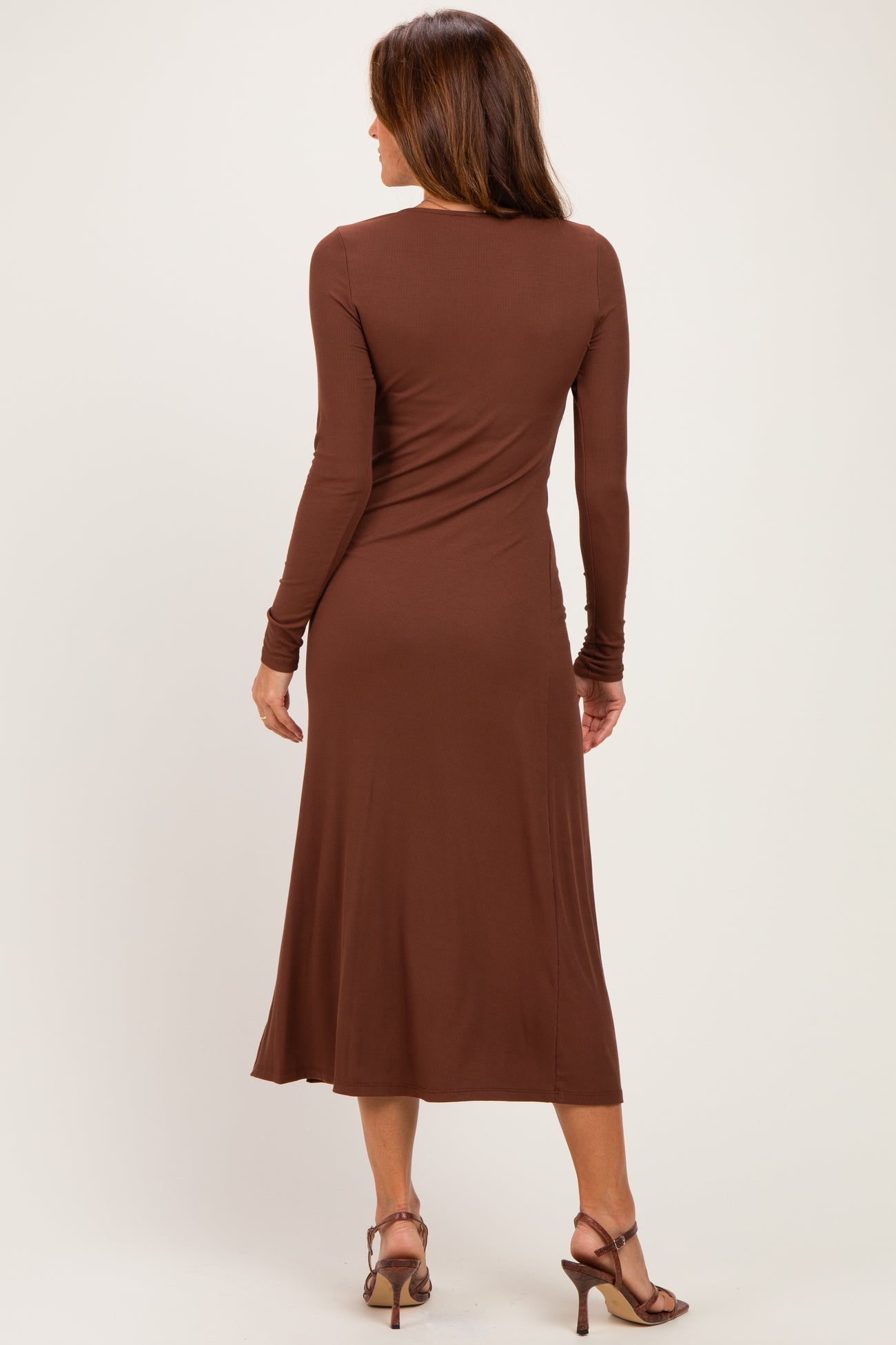 woman wearing a brown long sleeve midi dress with a fitted silhouette and a flared hem, seen from the back