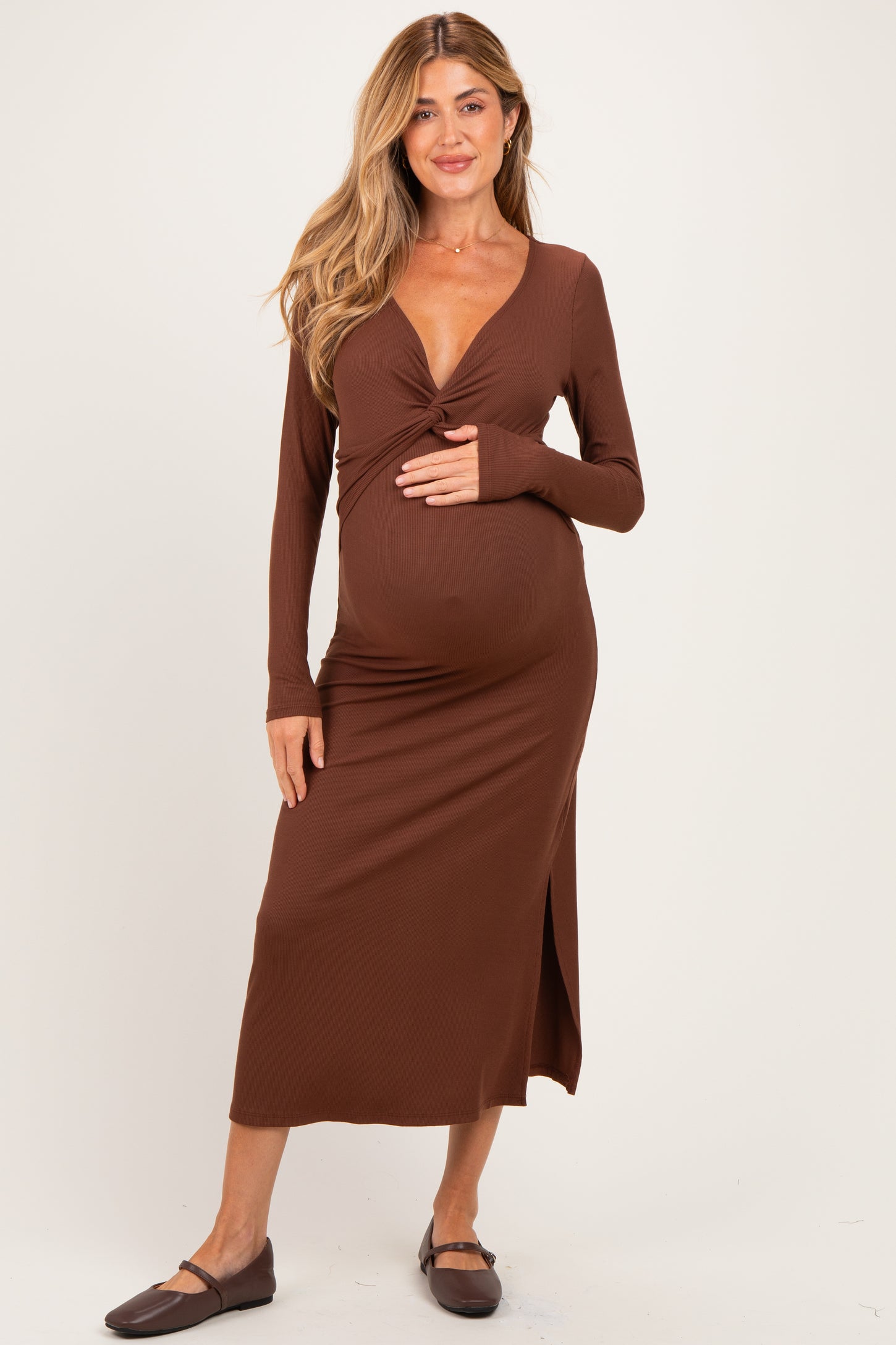 woman wearing a brown long sleeve maternity dress with a twisted front detail and showing her baby bump