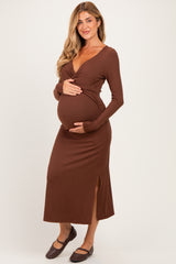 woman wearing a brown long sleeve maternity dress with a side slit and holding her baby bump