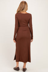 woman wearing a brown long sleeve maternity dress with a fitted silhouette and side slit, showing her baby bump from the back