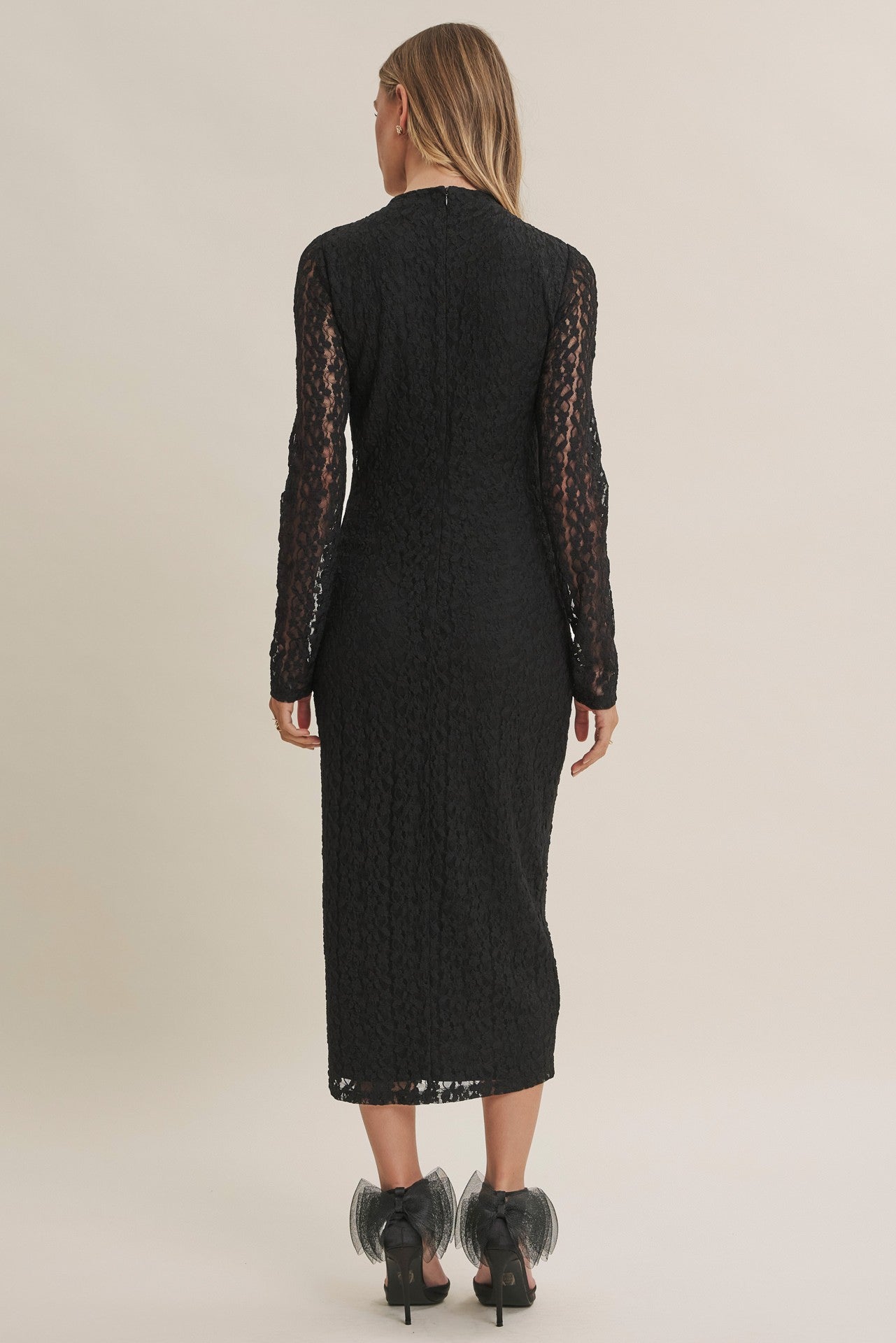 woman wearing a black lace long sleeve midi dress with a fitted silhouette, viewed from the back