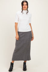 woman wearing a white short sleeve turtleneck top and a gray ribbed midi skirt, paired with black ankle boots