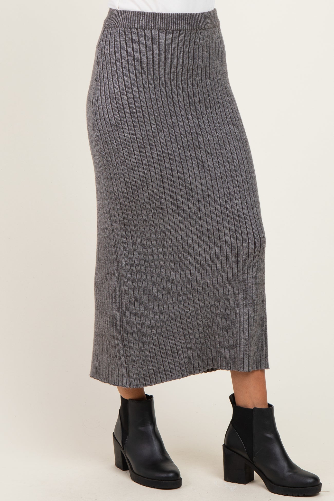 woman wearing a gray ribbed midi skirt with a fitted waistband and side slits, paired with black ankle boots
