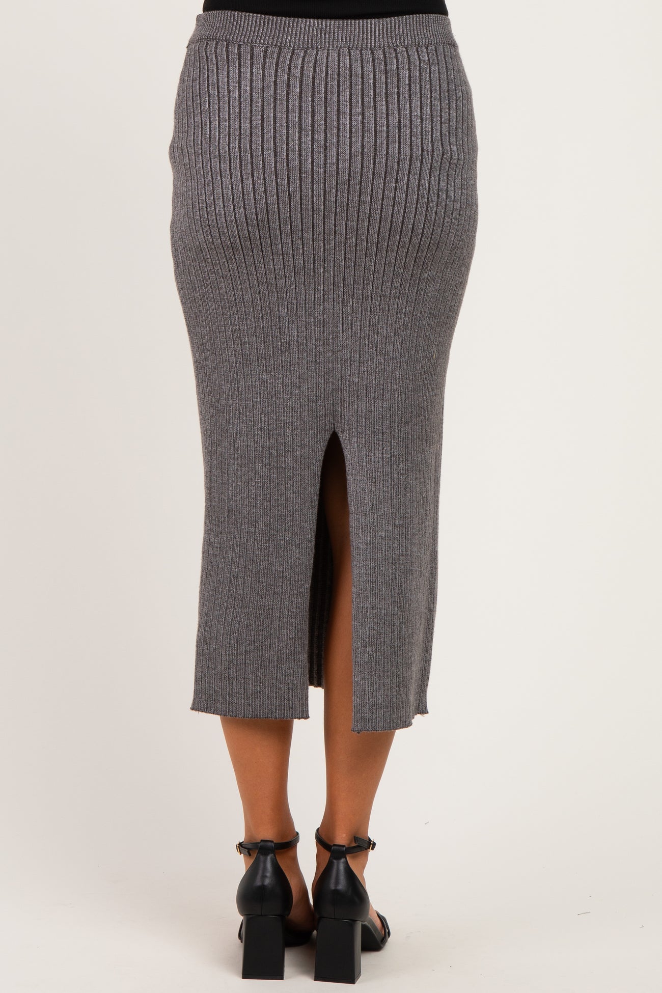woman wearing a gray ribbed maternity midi skirt with a back slit detail