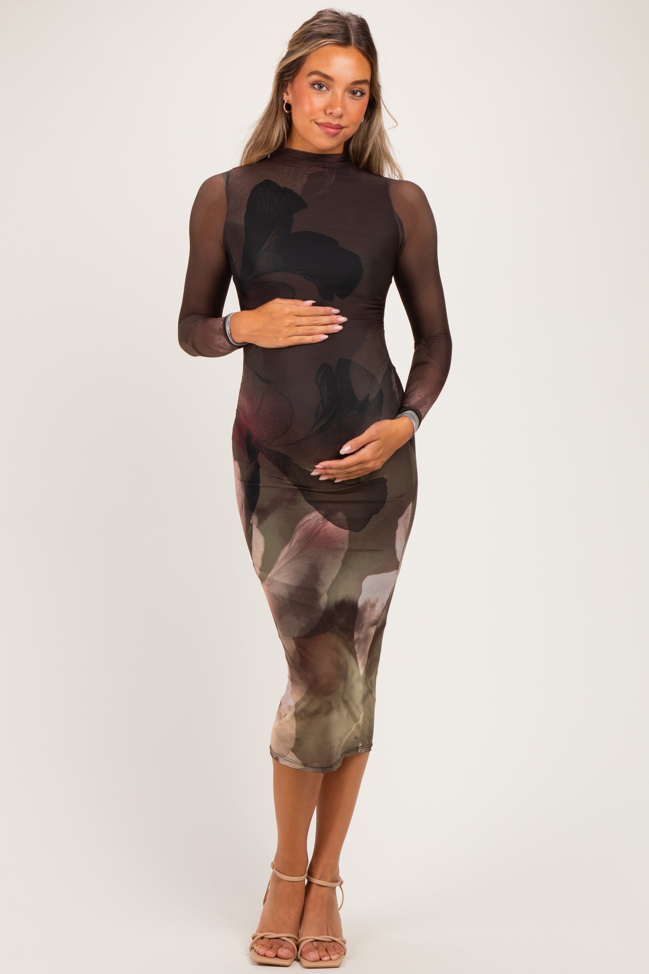 woman wearing a black long sleeve maternity dress with a floral print and holding her baby bump