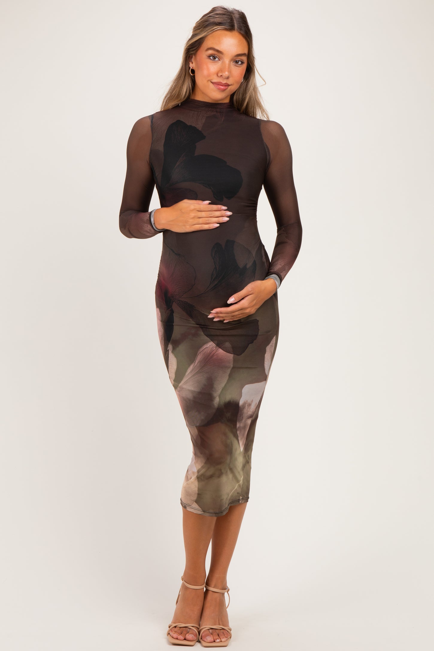 woman wearing a black long sleeve maternity dress with a floral print and holding her baby bump
