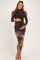 woman wearing a black long sleeve maternity dress with a floral print and holding her baby bump