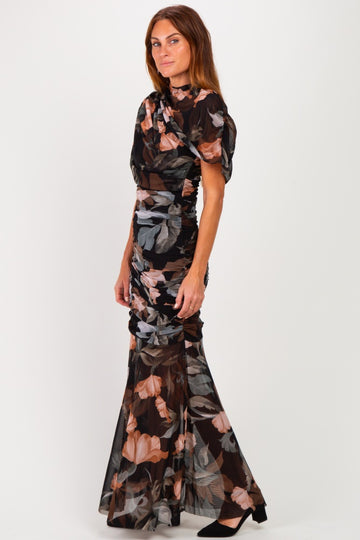 woman wearing a black floral printed evening gown with ruched details and a flared skirt