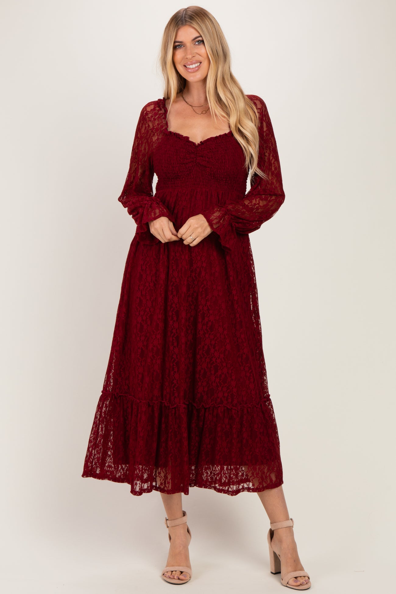 woman wearing a burgundy long sleeve lace midi dress with ruffles and a sweetheart neckline