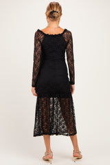 woman wearing a black lace maternity dress with long sleeves and a mid-length hem, showing a form-fitting silhouette