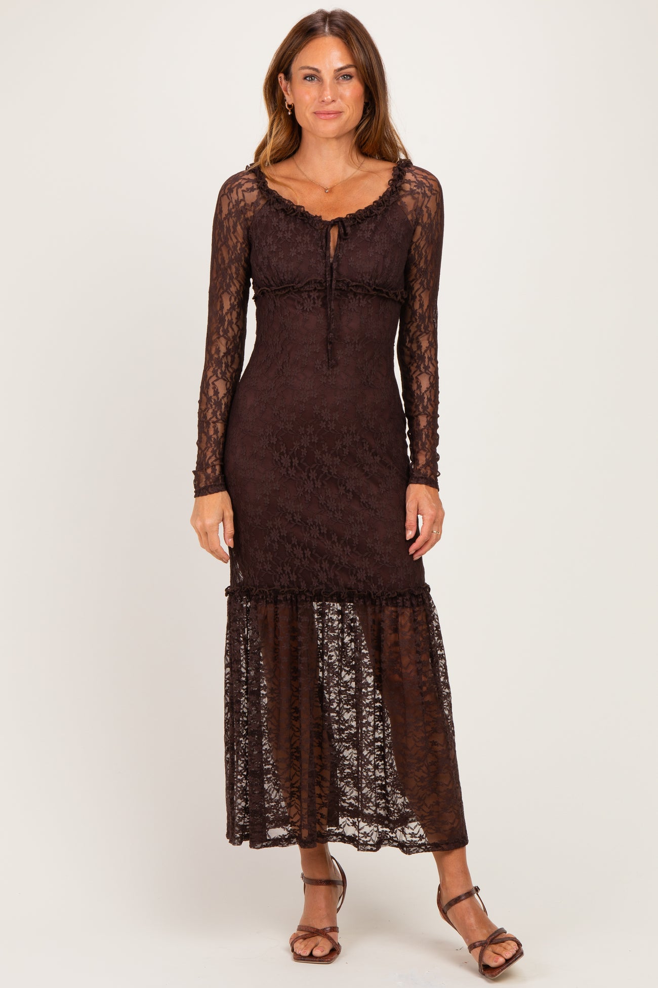 woman wearing a brown lace long sleeve maxi dress with a ruffled hem and a fitted bodice