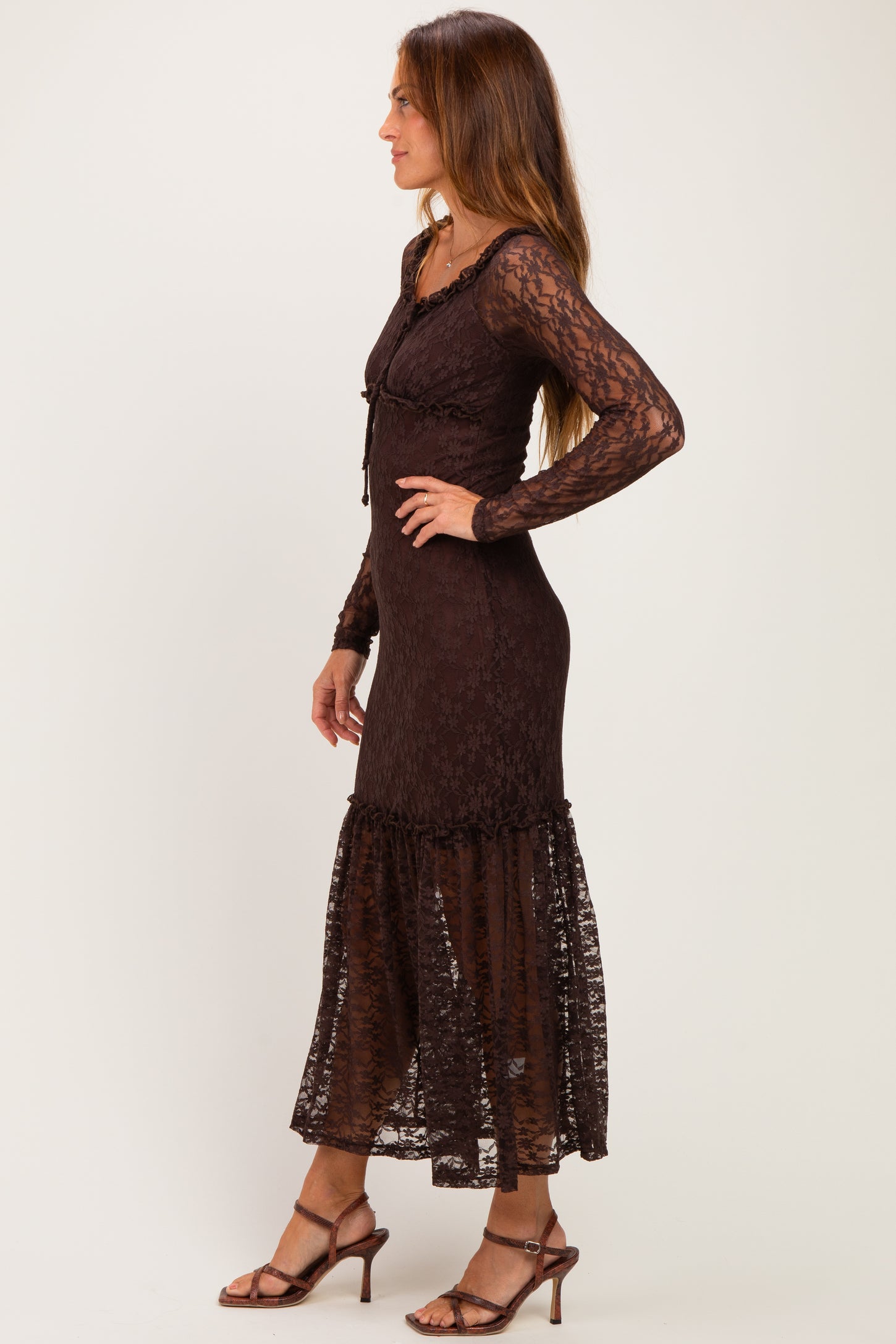 woman wearing a brown lace long sleeve maxi dress with a ruffled hem and a fitted bodice