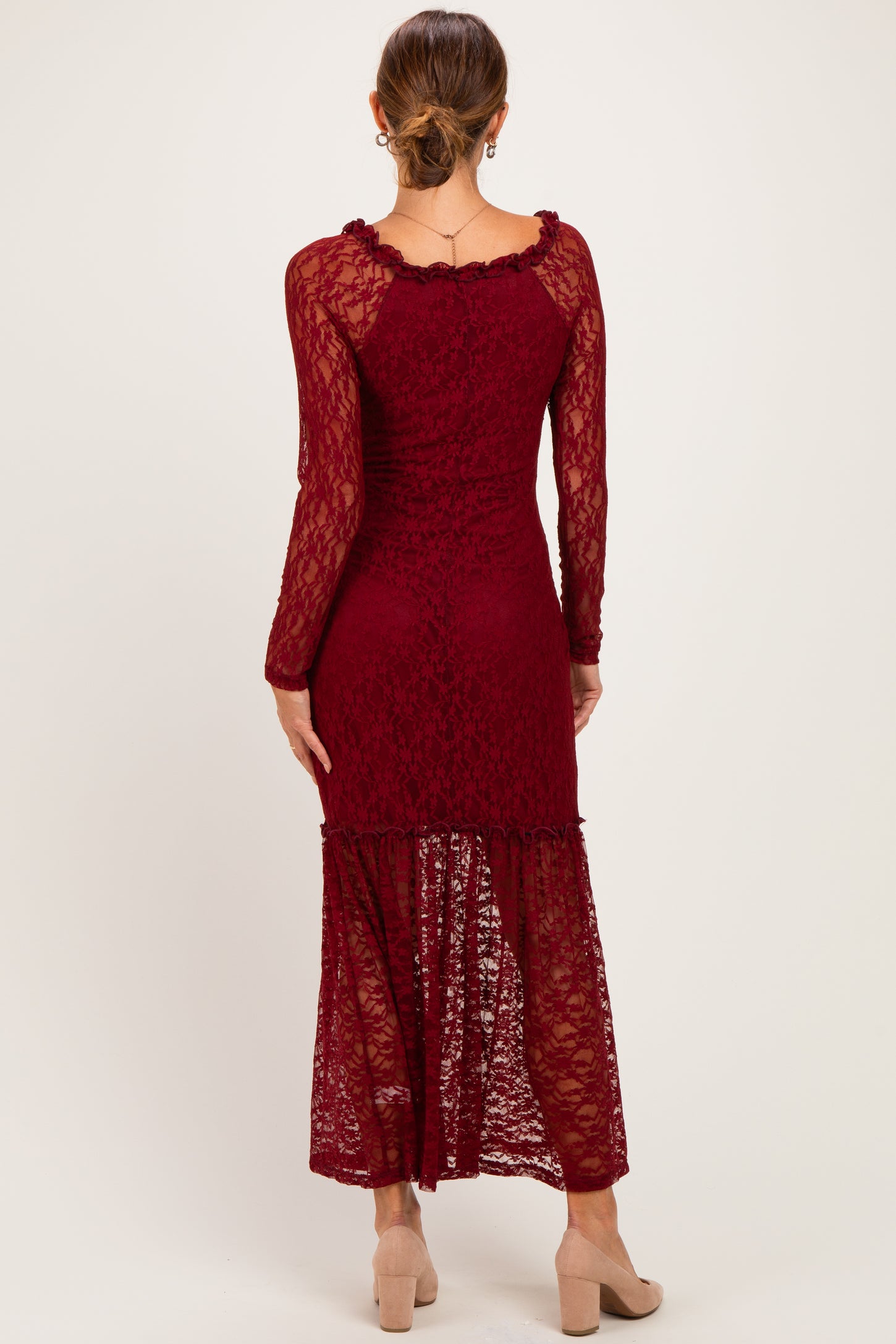 woman wearing a burgundy lace maxi dress with long sleeves and a tiered hem, viewed from the back