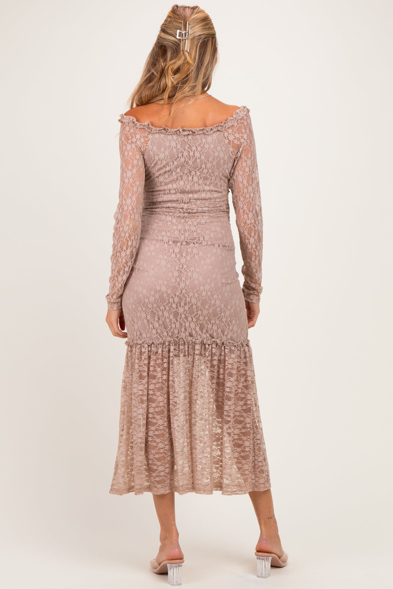 woman wearing a maternity lace long sleeve dress in a soft taupe color with a ruffled hem, viewed from the back