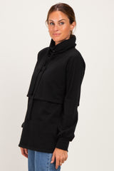 woman wearing a black long sleeve pullover hoodie with a high neck and drawstring detail, paired with blue jeans