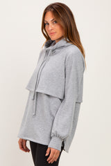 woman wearing a light gray oversized hoodie with a layered design and a drawstring neckline