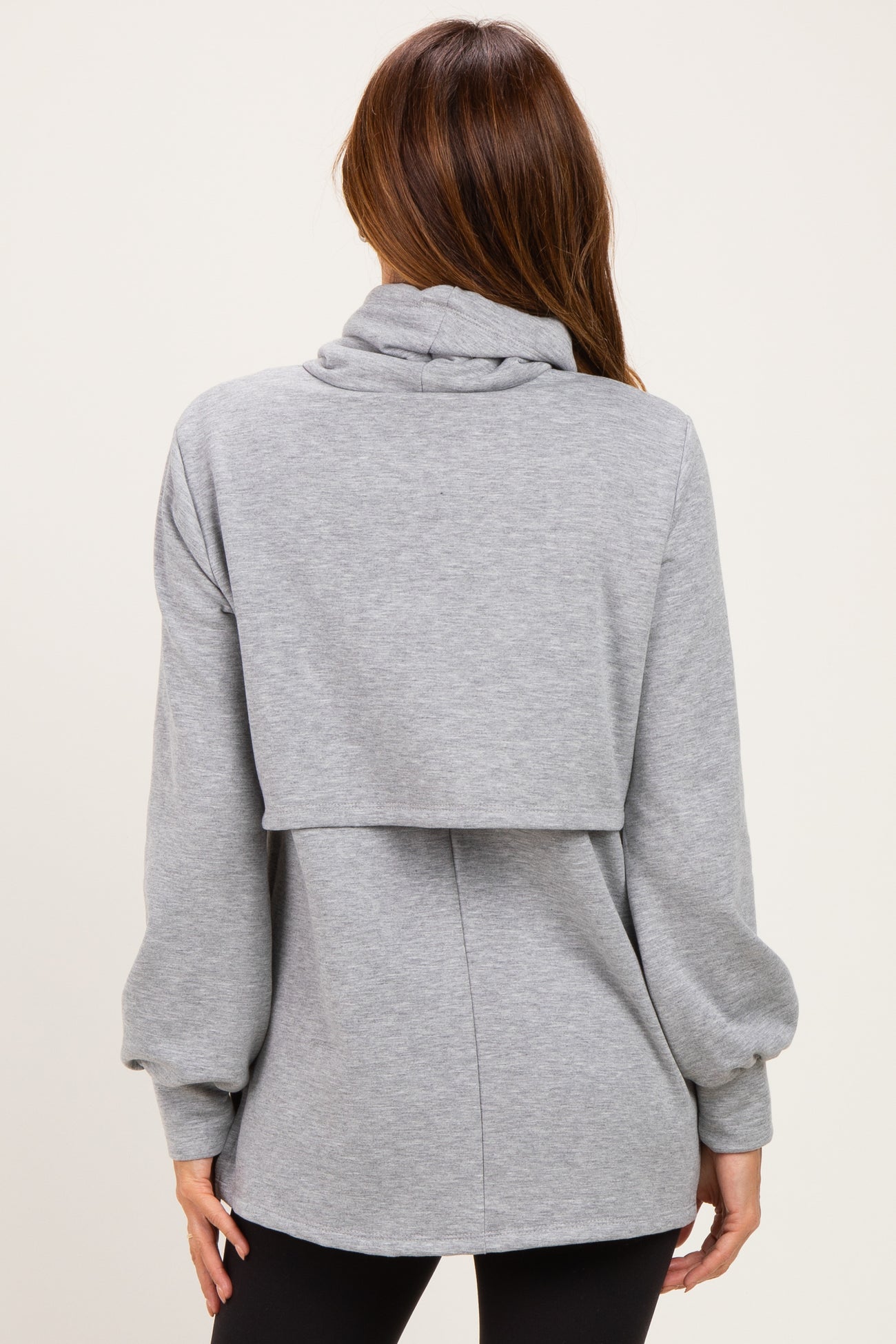 woman wearing a gray oversized sweatshirt with a cowl neck and layered back style, shown from the back
