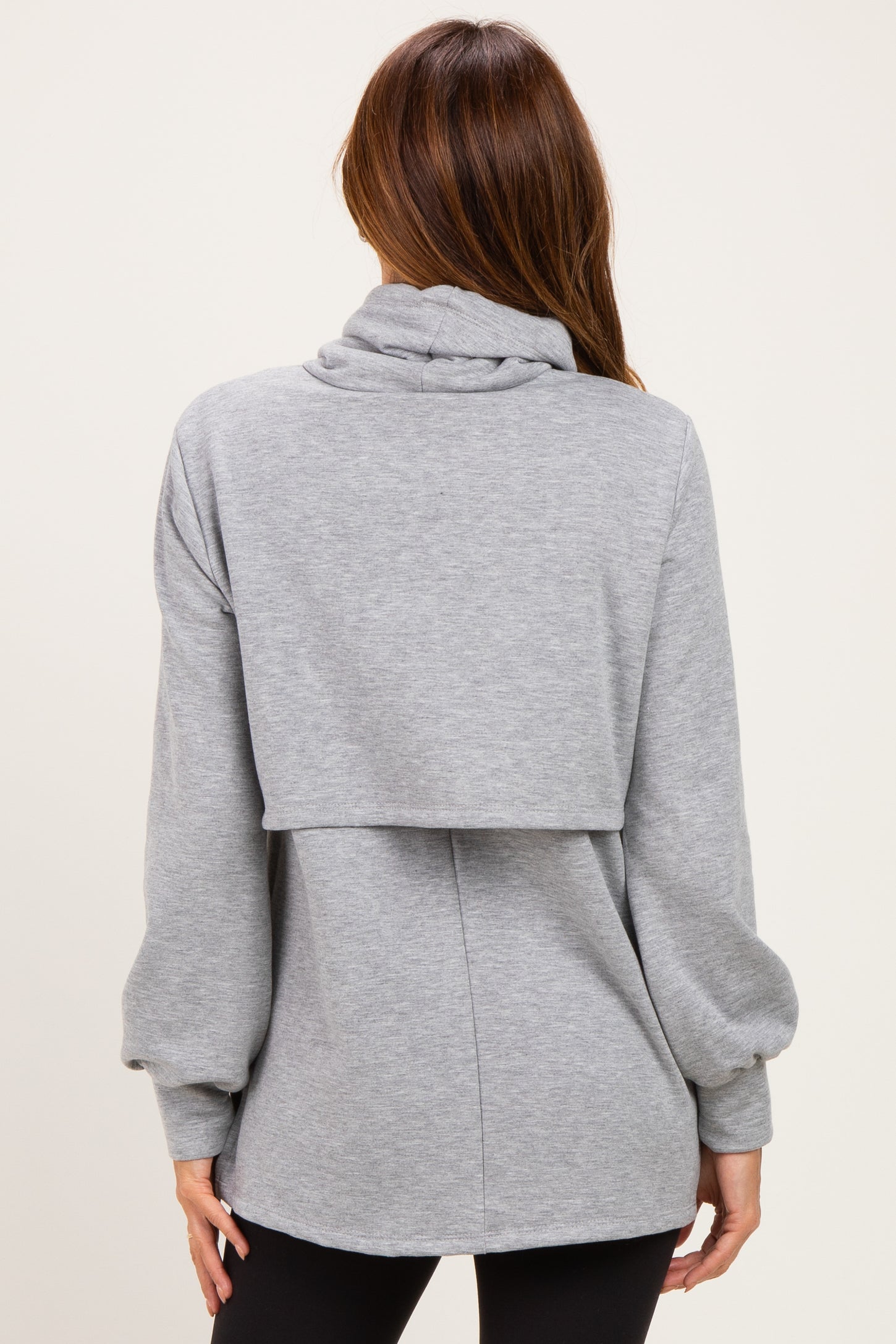 woman wearing a gray oversized sweatshirt with a cowl neck and layered back style, shown from the back
