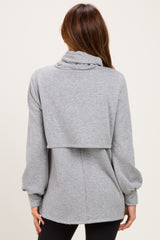 woman wearing a gray oversized sweatshirt with a cowl neck and layered back style, shown from the back