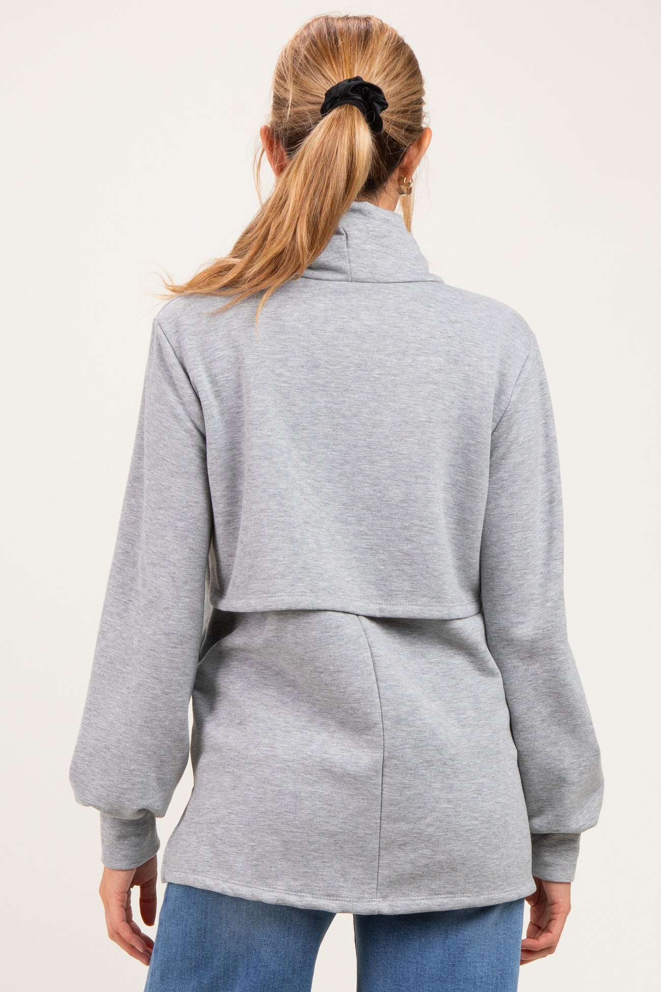 woman wearing a gray maternity pullover with a high collar and split back design, viewed from the back