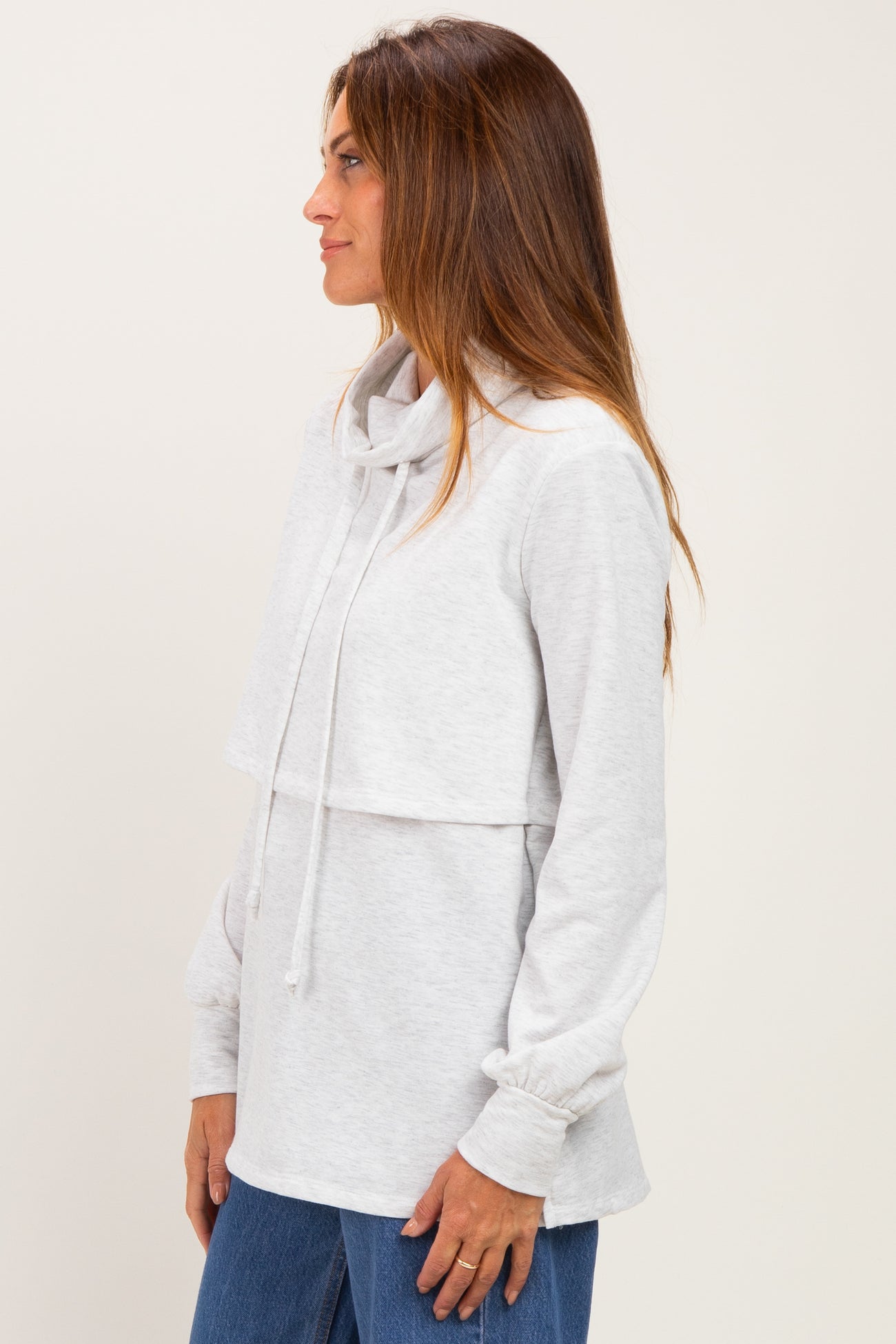 woman wearing a light gray cowl neck sweatshirt with a layered design and long sleeves