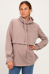 woman wearing a taupe cropped hoodie with a high neckline and side slits, styled with blue jeans