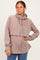 woman wearing a taupe cropped hoodie with a high neckline and side slits, styled with blue jeans