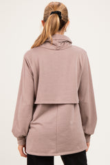 woman wearing a light brown maternity hoodie with a high-low hem and long sleeves, viewed from the back
