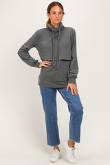 woman wearing a dark gray long sleeve cowl neck sweatshirt paired with light blue straight leg jeans and white sneakers