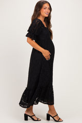 woman wearing a black lace maternity dress with short ruffled sleeves and a flowing hem, showing her baby bump