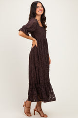 woman wearing a brown lace maxi dress with puff sleeves and a ruffled hem, standing sideways and smiling