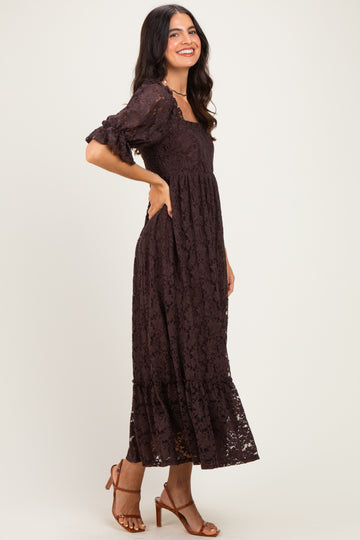 woman wearing a brown lace maxi dress with puff sleeves and a ruffled hem, standing sideways and smiling