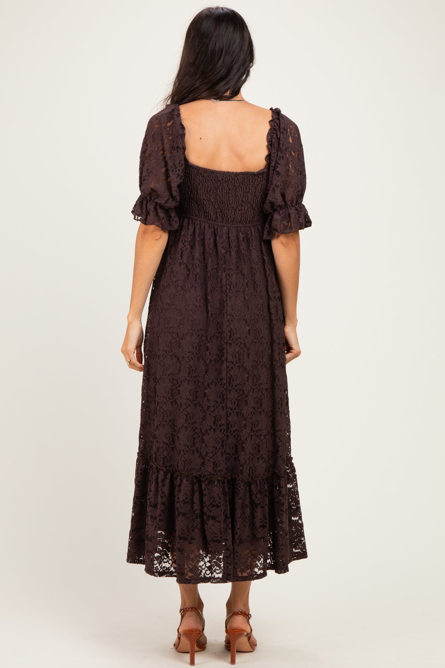 woman wearing a chocolate brown lace maxi dress with short puff sleeves and a tiered skirt, viewed from the back