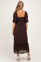woman wearing a brown lace maternity dress with puff sleeves and a tiered hem, showing a baby bump