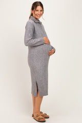 woman wearing a gray knitted maternity sweater dress with side slits and holding her baby bump