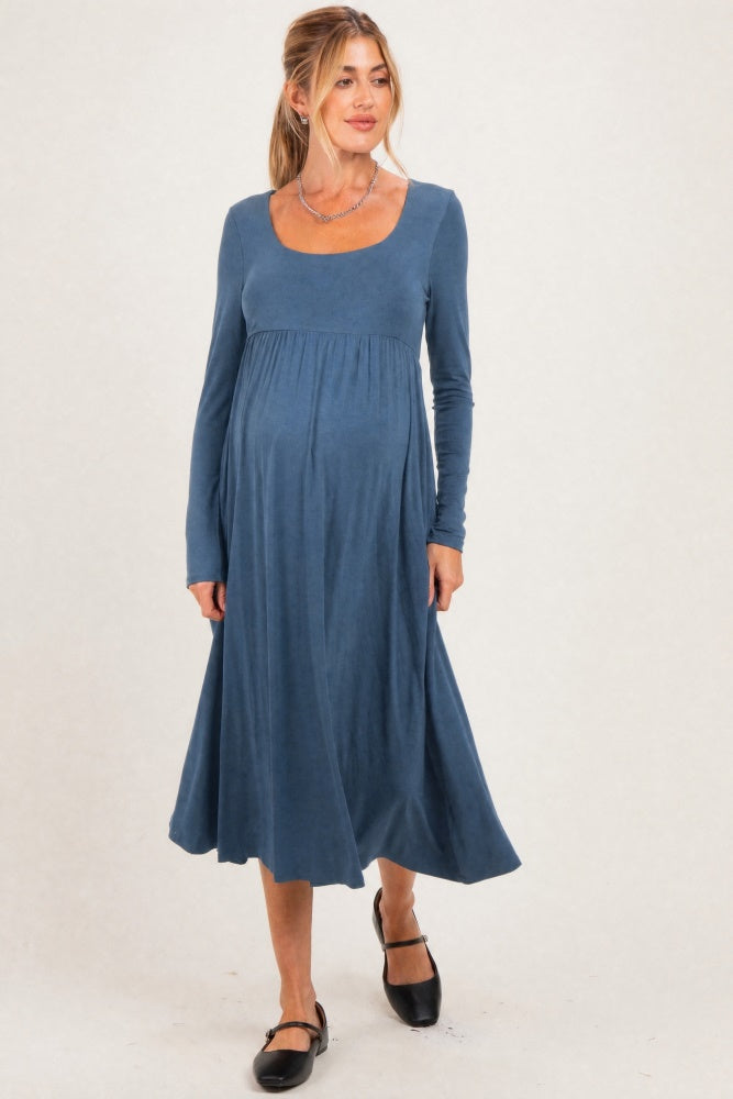woman wearing a long sleeve blue maternity dress with a scoop neckline and flowing skirt, showcasing her baby bump