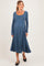 woman wearing a long sleeve blue maternity dress with a scoop neckline and flowing skirt, showcasing her baby bump