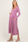 woman wearing a lilac long sleeve maternity dress with pockets and gently holding her baby bump