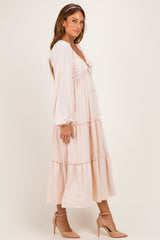 woman wearing a soft pink long sleeve midi dress with a tiered skirt and heels