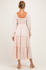 woman wearing a pale pink three-tiered maternity dress with long sleeves and a square neckline