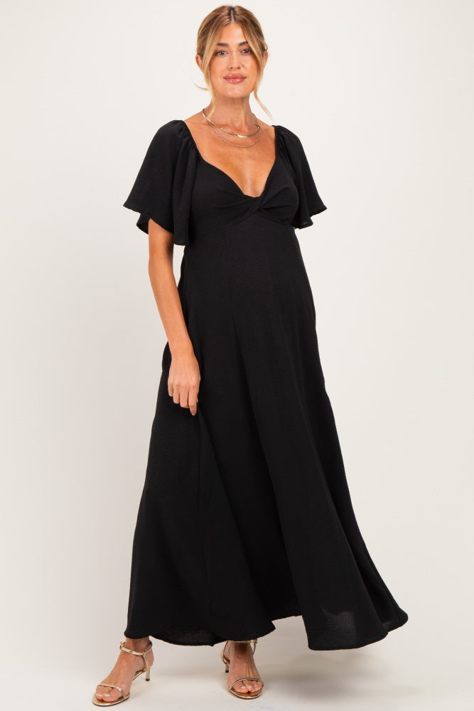 woman wearing a black maternity maxi dress with flutter sleeves and a fitted bodice, showing a baby bump
