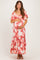 woman wearing a pink floral maternity maxi dress and cradling her baby bump