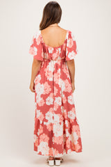 woman wearing a coral floral maternity maxi dress with short sleeves and a tiered hem, showing her baby bump from the back