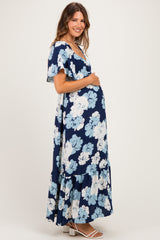 woman wearing a navy blue floral maternity maxi dress with flutter sleeves and a visible baby bump
